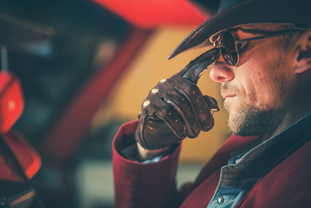 Man in car with cowboy hat and gloves