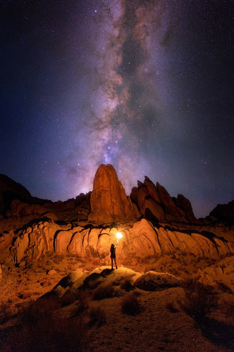 Person in foreground of galaxy with rock formation